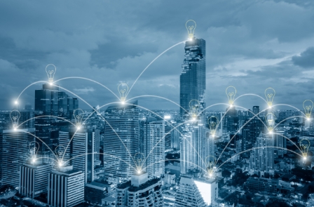 City skyline with lightbulb icons connected by lines, symbolizing smart city connectivity.