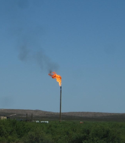 Natural gas flare from a tall methane pipe in a field.