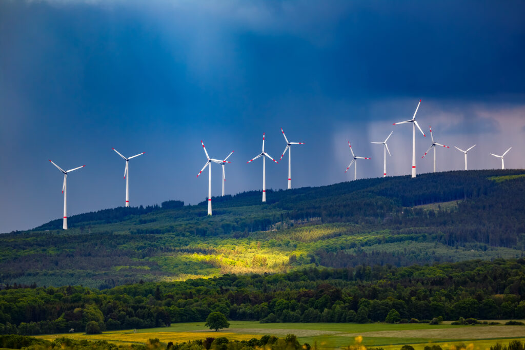 Wind turbines on a hill under a stormy sky.