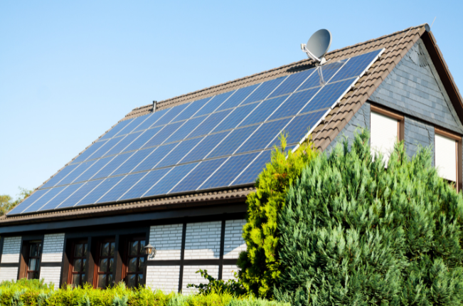 Suburban house with dark-tile roof covered in blue solar panels