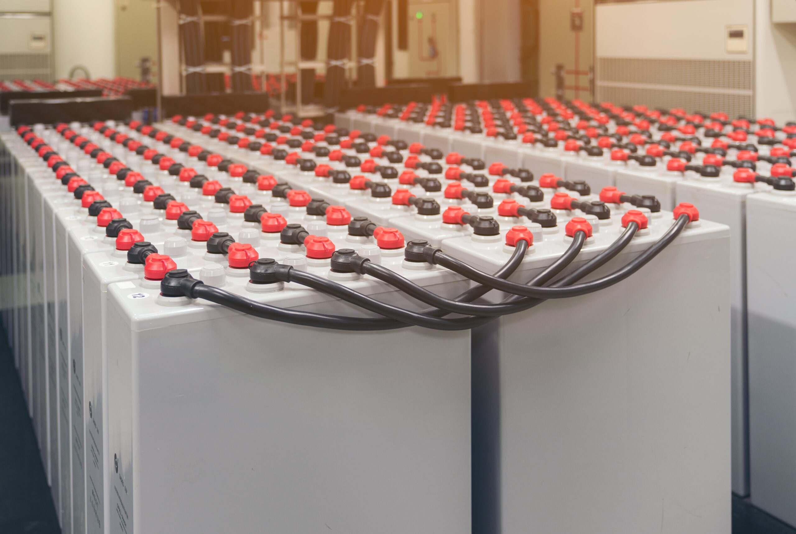 Rows of large industrial batteries connected by thick black cables.