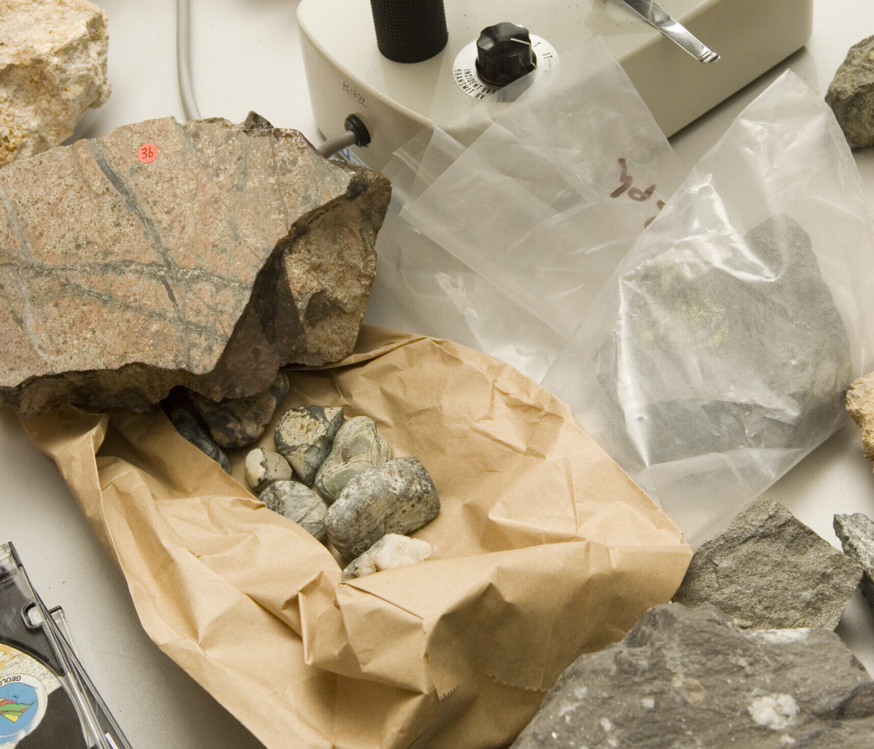 Microscope in geology lab, with rocks around it.